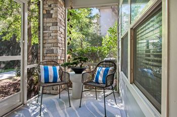 a porch with two chairs and a table on it